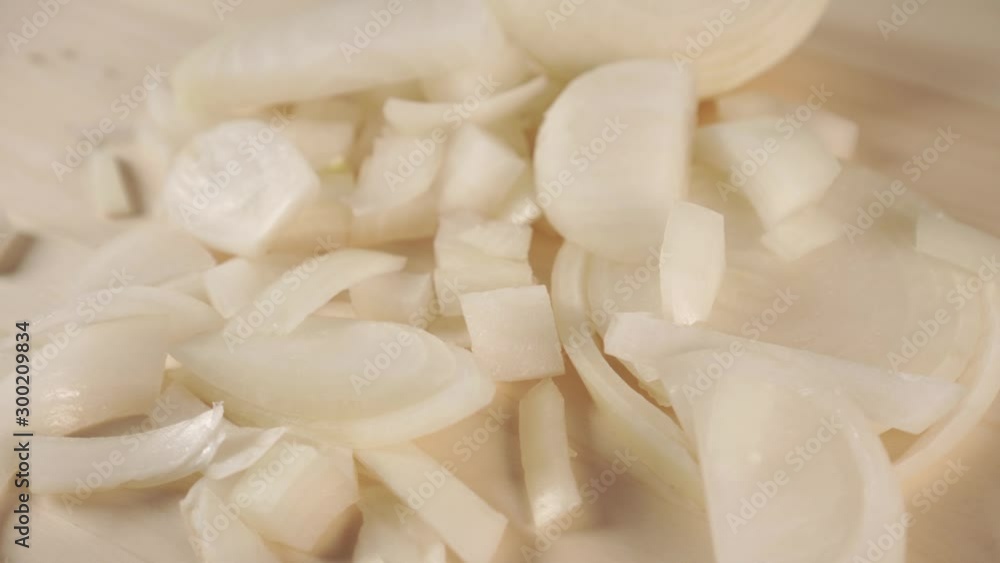 Sliced in small and large pieces, white onion rotates on a wooden cutting board. Cooking Delicious Spices Sliced in small and large pieces, white onion rotates on a wooden cutting board. Cooking Delicious Spices