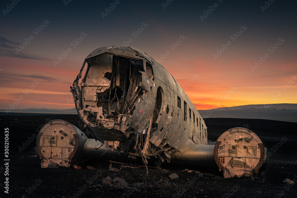Crushed plane Dakota on black beach at the sunset
