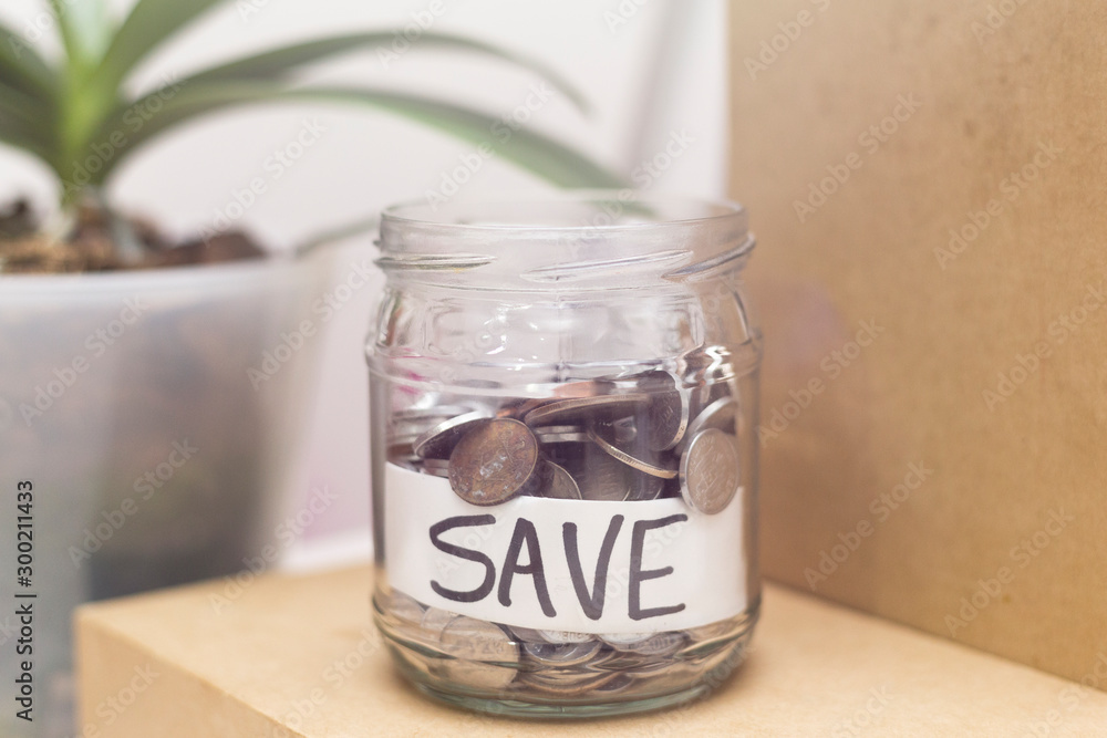 Jar with coins and inscription SAVE. Economy and finance prosperity concept. Saving income and money management idea, represented by a jar full of metalic coins on modern background. Jar with coins and inscription SAVE. Economy and finance prosperity concept. Saving income and money management idea, represented by a jar full of metalic coins on modern background.