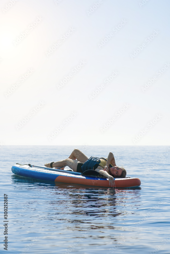 Fototapeta premium Summer holidays vacation travel. SUP Stand up paddle board. Young woman sailing on beautiful calm lagoon