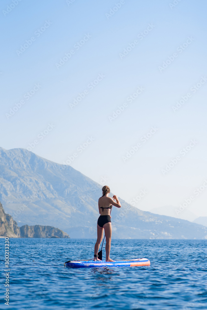 Summer holidays vacation travel. SUP Stand up paddle board. Young woman sailing on beautiful calm lagoon