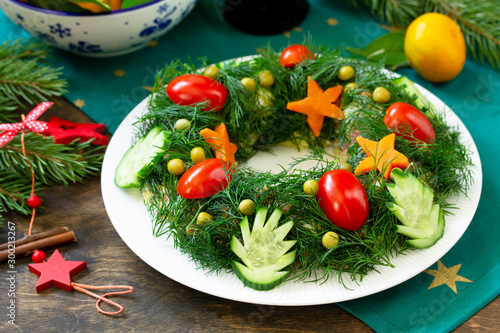 Winter Christmas salad wreath. Delicious Russian traditional salad "Olivier" with vegetables and meat on the holiday table.