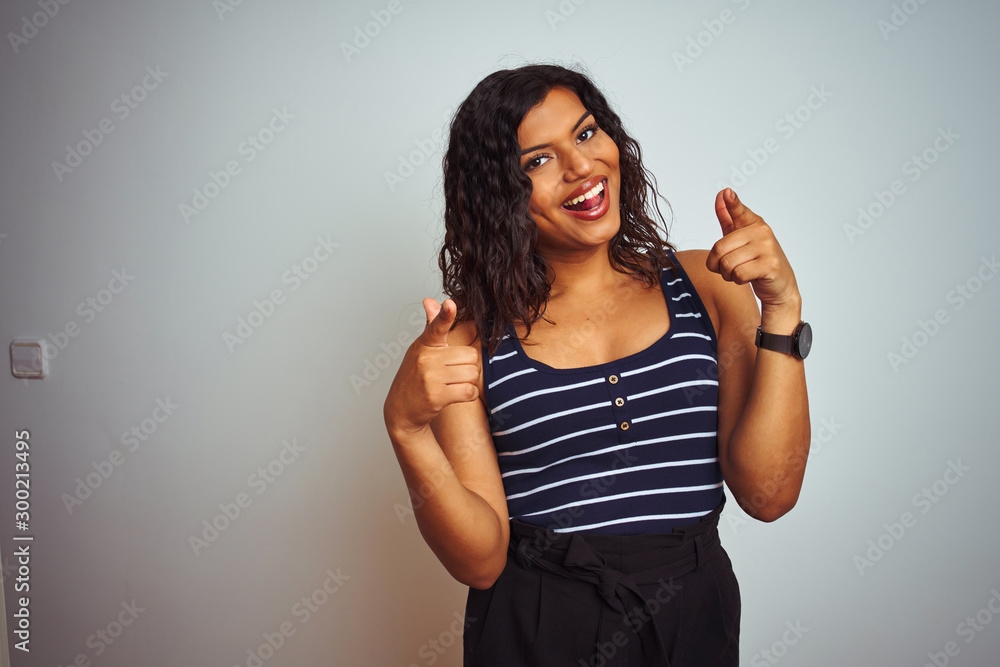 Transsexual transgender woman wearing striped t-shirt over isolated white background pointing fingers to camera with happy and funny face. Good energy and vibes. Transsexual transgender woman wearing striped t-shirt over isolated white background pointing fingers to camera with happy and funny face. Good energy and vibes.