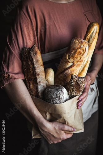 French baguettes in female hands on a black background. homemade baking