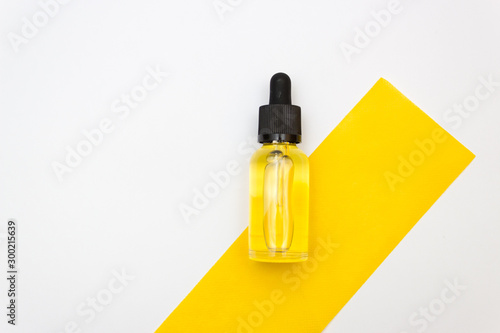 Medical bottle with a pipette, filled with transparent yellow liquid isolated over the white background