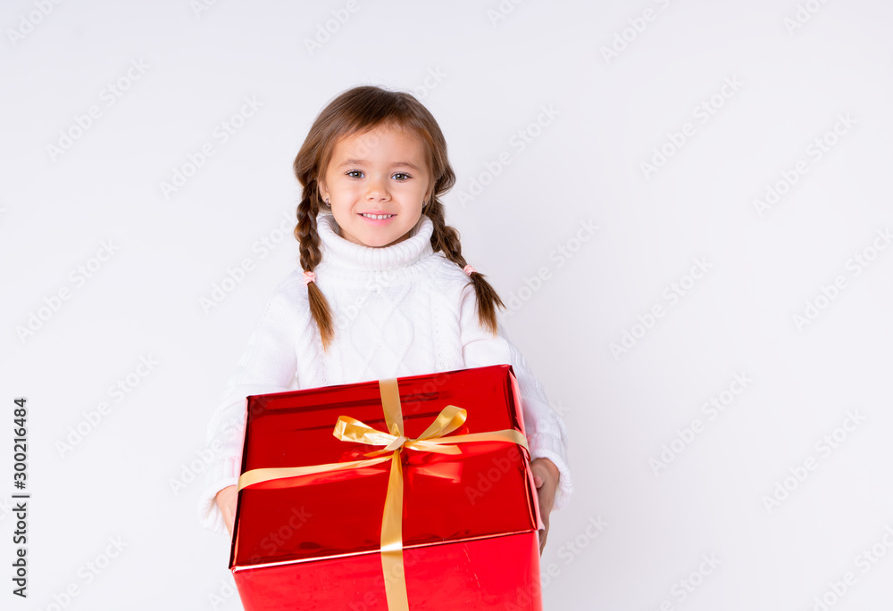 little cute girl in knitted white sweater holding a present in studio. Concept Christmas, New Year, Birthday little cute girl in knitted white sweater holding a present in studio. Concept Christmas, New Year, Birthday