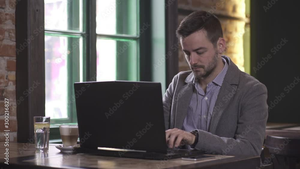Portrait of young Caucasian man while working on laptop computer in coffee shop Portrait of young Caucasian man while working on laptop computer in coffee shop