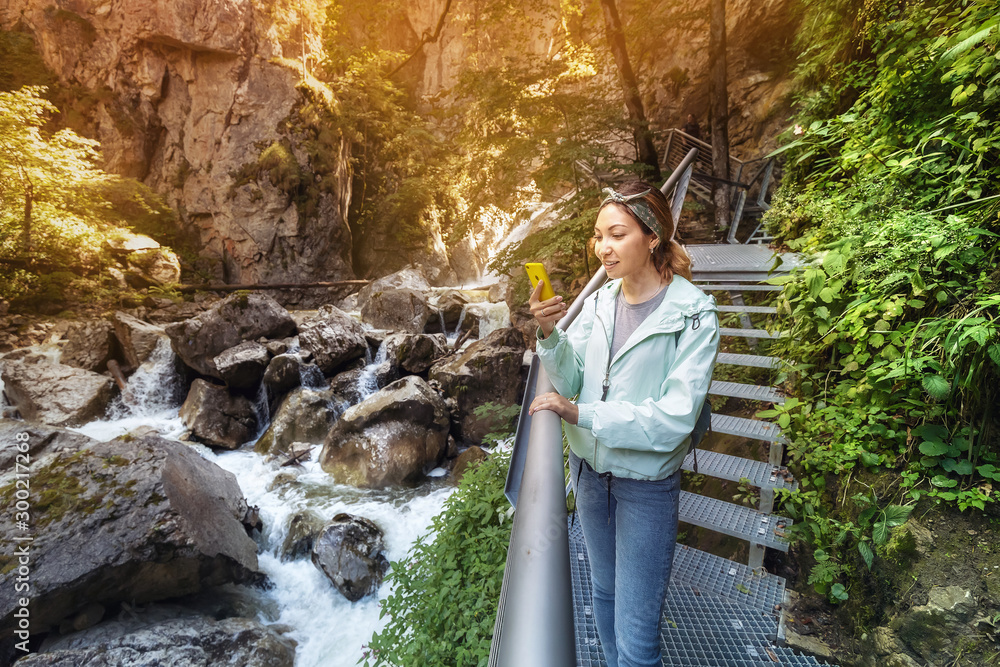 Happy asian tourist girl walk along a hinged iron trail along sheer cliffs in the canyon of the Pollat river in the Bavarian Alps Happy asian tourist girl walk along a hinged iron trail along sheer cliffs in the canyon of the Pollat river in the Bavarian Alps