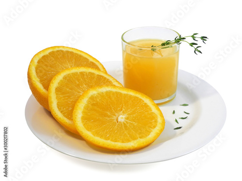 Glass of orange juice and fresh sliced orange on white plate decorated with sprigs of thyme, isolated on white background  