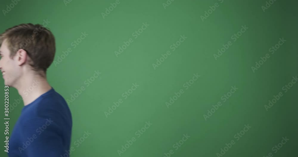 Friendly young man waving hand greeting hello over green background Friendly young man waving hand greeting hello over green background