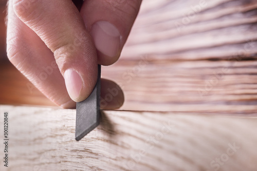 carpenter using  rasp or file handles wooden oak plank
