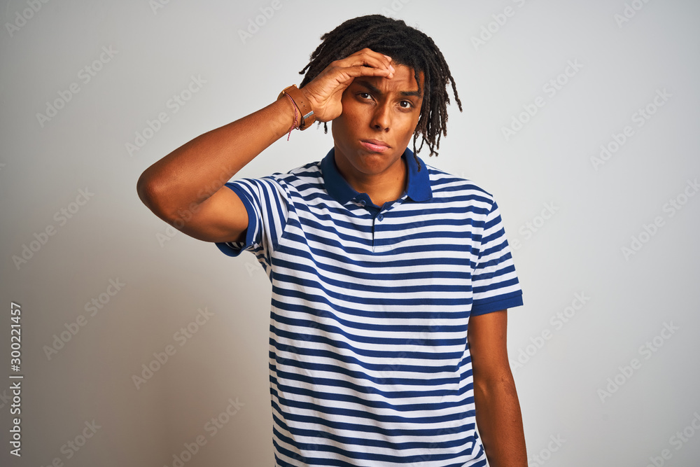 Afro man with dreadlocks wearing striped blue polo standing over isolated white background worried and stressed about a problem with hand on forehead, nervous and anxious for crisis Afro man with dreadlocks wearing striped blue polo standing over isolated white background worried and stressed about a problem with hand on forehead, nervous and anxious for crisis