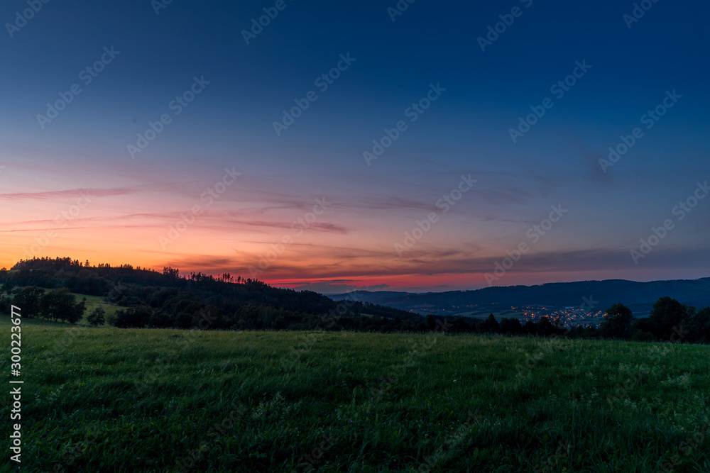 Obraz premium Multi colored sky of hill Velka Lhota Beskydy area sky and clouds play with many colors with view to surround the nature area around many small hills and mountains around capturing during sunset.