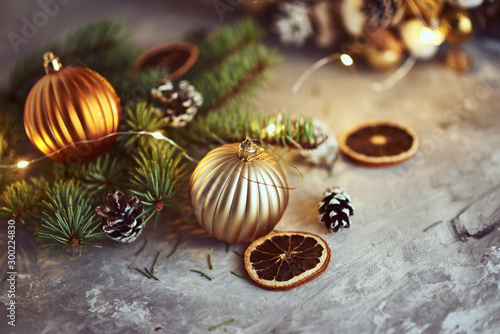 Christmas decorations with golden balls, fir tree branch and garland lights on a dark background