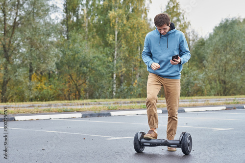 Man riding on the hoverboard and using smartphone outdoor photo