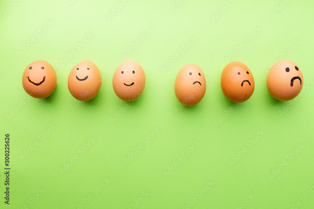 Smiling and sad eggs on a green background Smiling and sad eggs on a green background