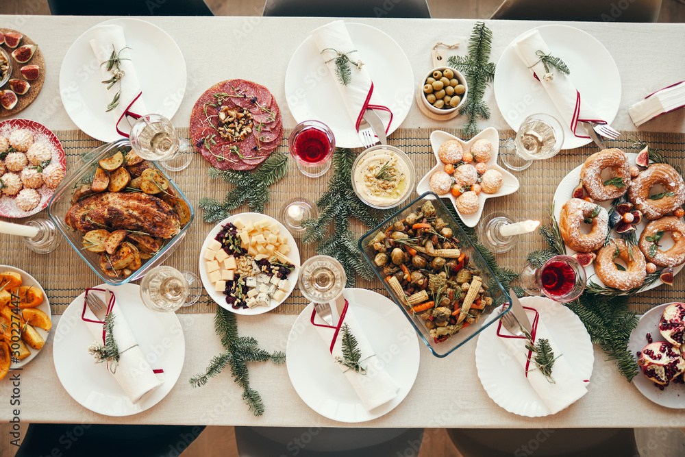 Top view background of beautiful Christmas table with delicious homemade food decorated with fir branches, copy space - obrazy, fototapety, plakaty 