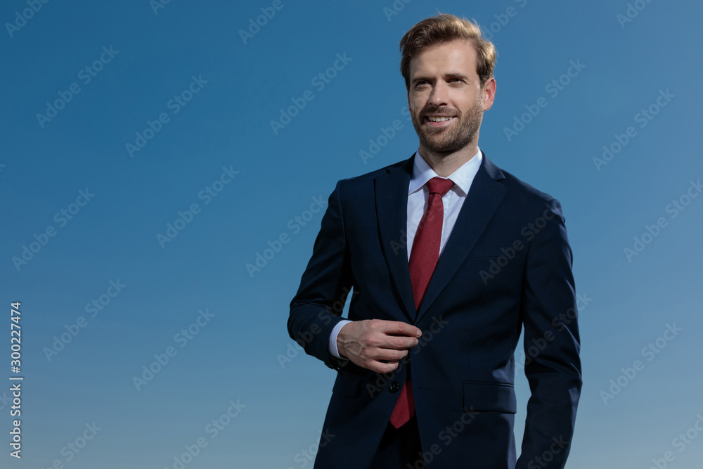 Positive businessman fixing his jacket and smiling Positive businessman fixing his jacket and smiling