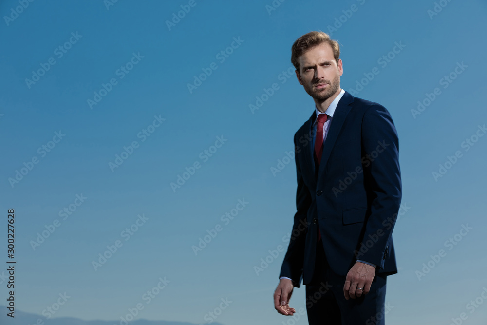 Bothered young businessman looking away and frowning Bothered young businessman looking away and frowning