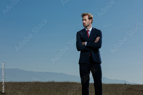 Pensive businessman looking away with his arms folded