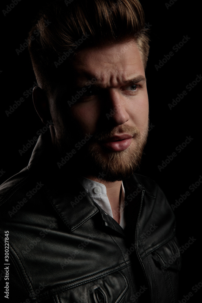 charming casual man wearing leather jacket looking away suspicious