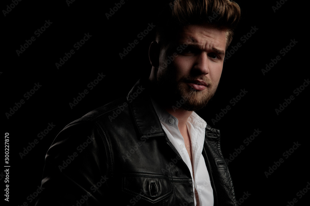 man wearing leather jacket standing aside and looking the other