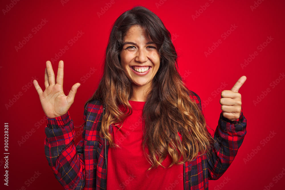 Young beautiful woman wearing casual jacket standing over red isolated background approving doing positive gesture with hand, thumbs up smiling and happy for success. Winner gesture. Young beautiful woman wearing casual jacket standing over red isolated background approving doing positive gesture with hand, thumbs up smiling and happy for success. Winner gesture.