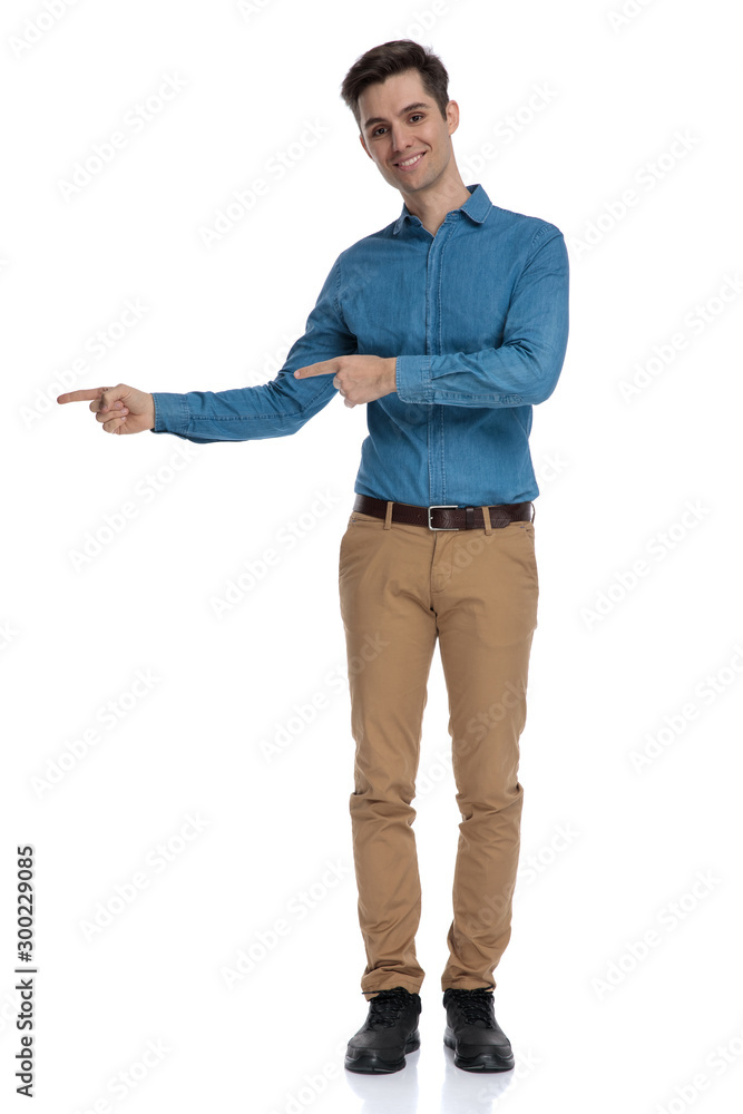 happy young man in blue shirt pointing finger to side happy young man in blue shirt pointing finger to side