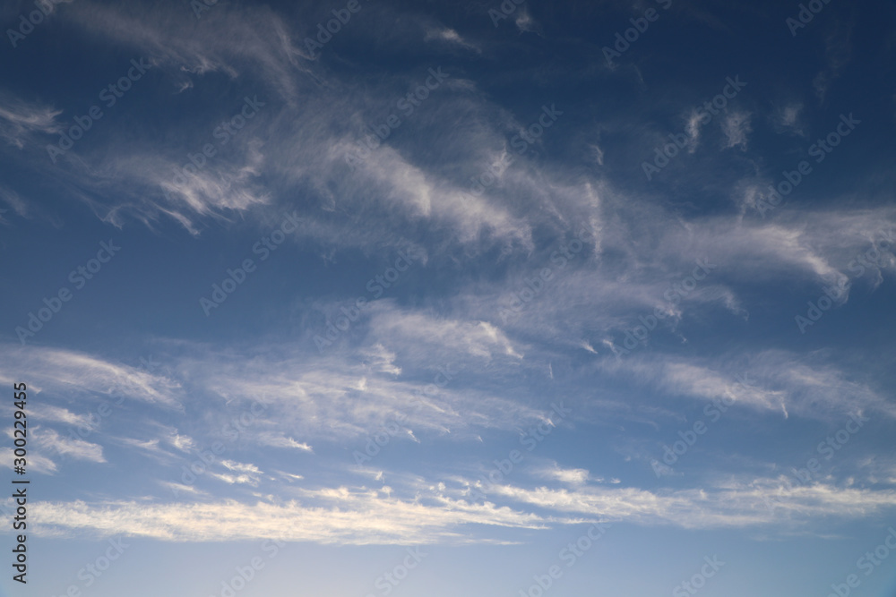 Cirrus clouds scattered across a bright blue sky
