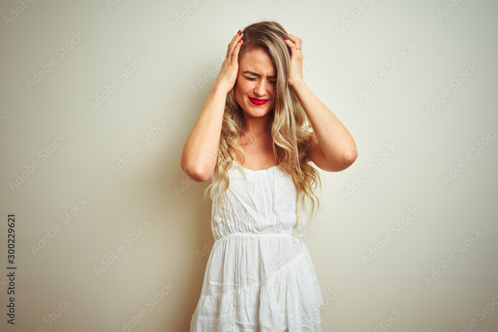 Young beautiful woman wearing casual dress standing over white isolated background suffering from headache desperate and stressed because pain and migraine. Hands on head.