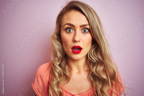 Young beautiful woman wearing t-shirt standing over pink isolated background scared in shock with a surprise face, afraid and excited with fear expression