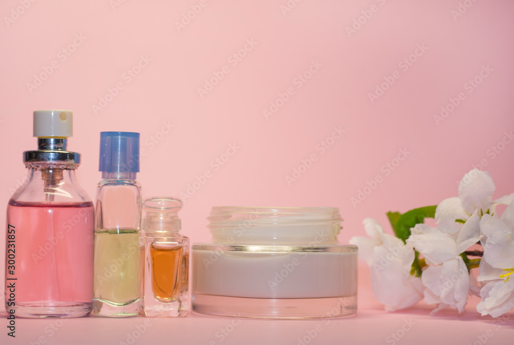 Woman, beauty and cosmetics concept: a bottles with liquid perfume at pink background Woman, beauty and cosmetics concept: a bottles with liquid perfume at pink background