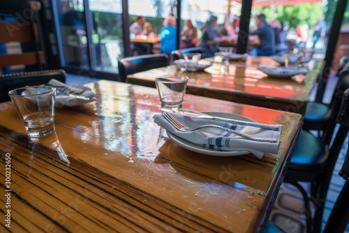 Table setting of cups, napkins, plates, and utensils in casual restaurant