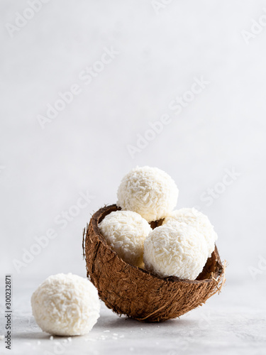 Coconut bliss balls in coconut shells on white gray background closeup view photo