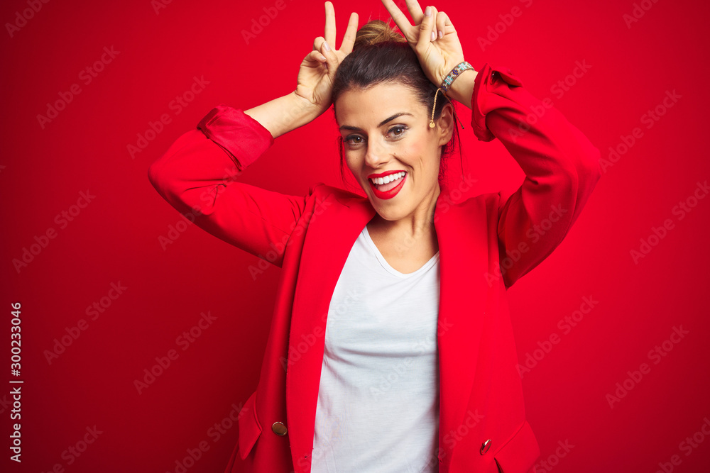 Young beautiful business woman standing over red isolated background Posing funny and crazy with fingers on head as bunny ears, smiling cheerful Young beautiful business woman standing over red isolated background Posing funny and crazy with fingers on head as bunny ears, smiling cheerful