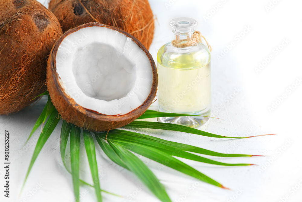 Coconut palm oil in a bottle with coconuts and green palm tree leaf isolated on a white background. Border design. Wide angle. Healthy Food, skin care concept. Vegan food Coconut palm oil in a bottle with coconuts and green palm tree leaf isolated on a white background. Border design. Wide angle. Healthy Food, skin care concept. Vegan food