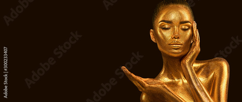 Fashion art Golden skin Woman face portrait closeup. Model girl with holiday golden Glamour shiny makeup. Sequins. Gold jewellery, jewelry, accessories. Beauty gold metallic body, Lips and Skin