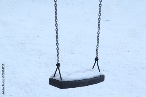 sparkling texture of natural white snow on a child's lonely swing in winter