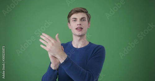 Handsome young man clapping and encouraging over green background photo