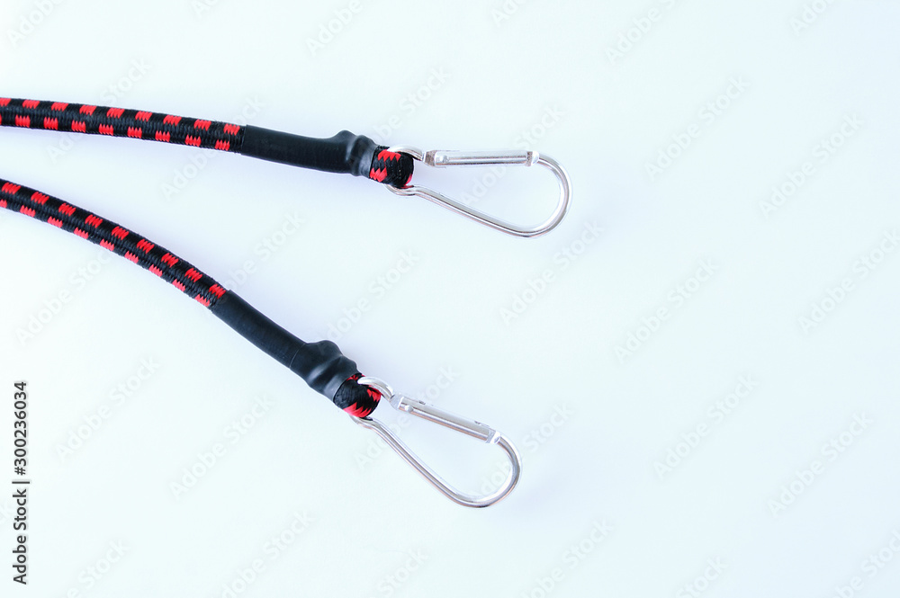 Obraz premium The ends of a rubber cord to secure luggage with metal carabiners on a white background.