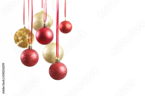 Gold and red Christmas shiny balls hanging in front of white background. Large glitter Christmas ornaments.