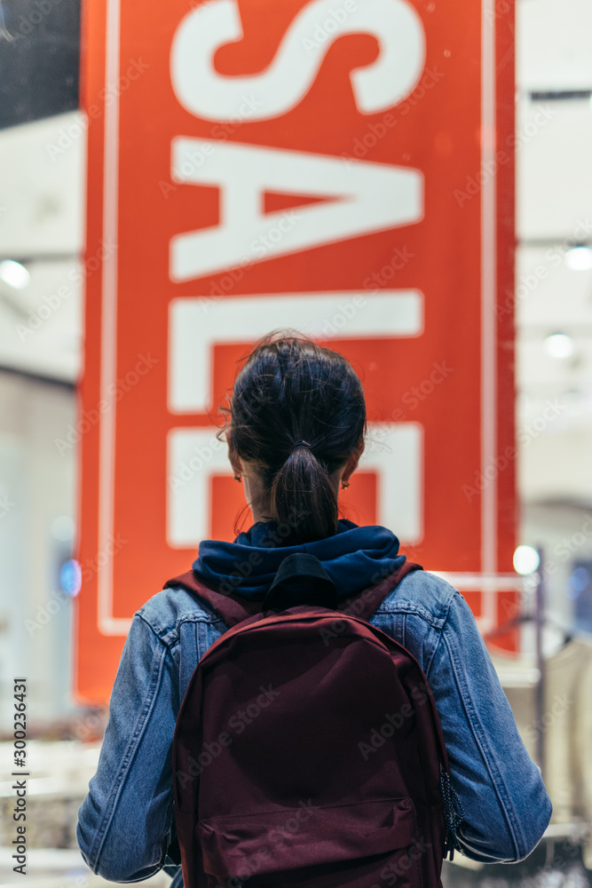 Fototapeta premium Girl looks at the window of the shopping center.