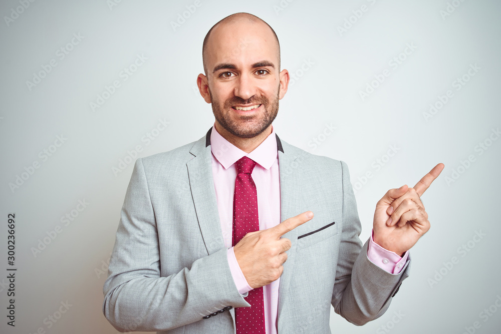 Young business man wearing suit and purple tie over isolated background smiling and looking at the camera pointing with two hands and fingers to the side.