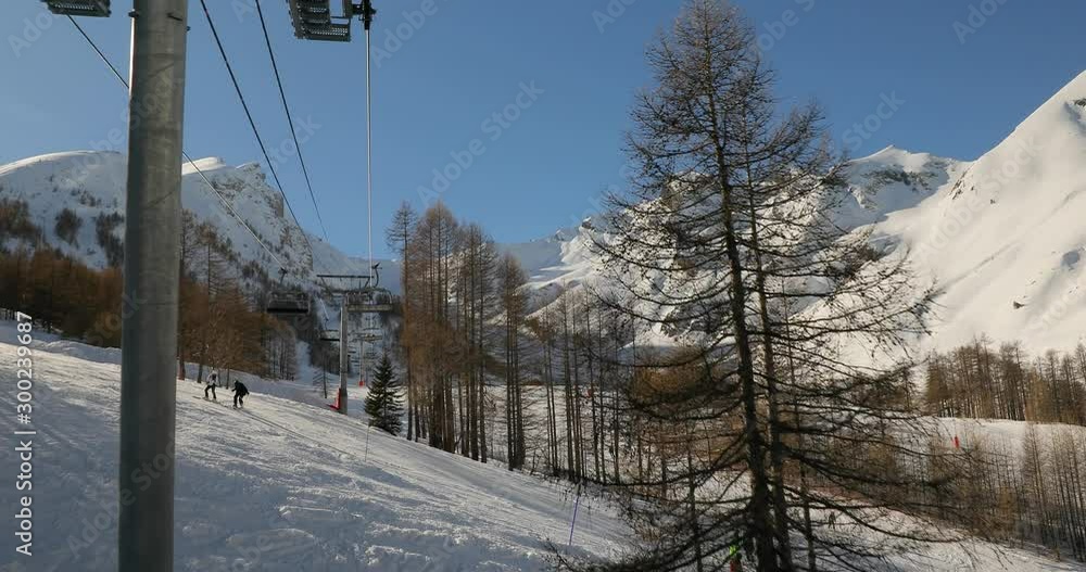 Using ski lift in the Alps, beautiful snowy mountain landscape with sum sunlight flares Using ski lift in the Alps, beautiful snowy mountain landscape with sum sunlight flares