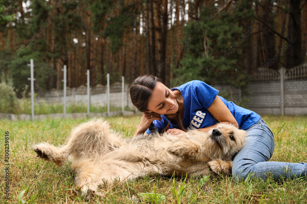Female volunteer with homeless dog at animal shelter outdoors Female volunteer with homeless dog at animal shelter outdoors
