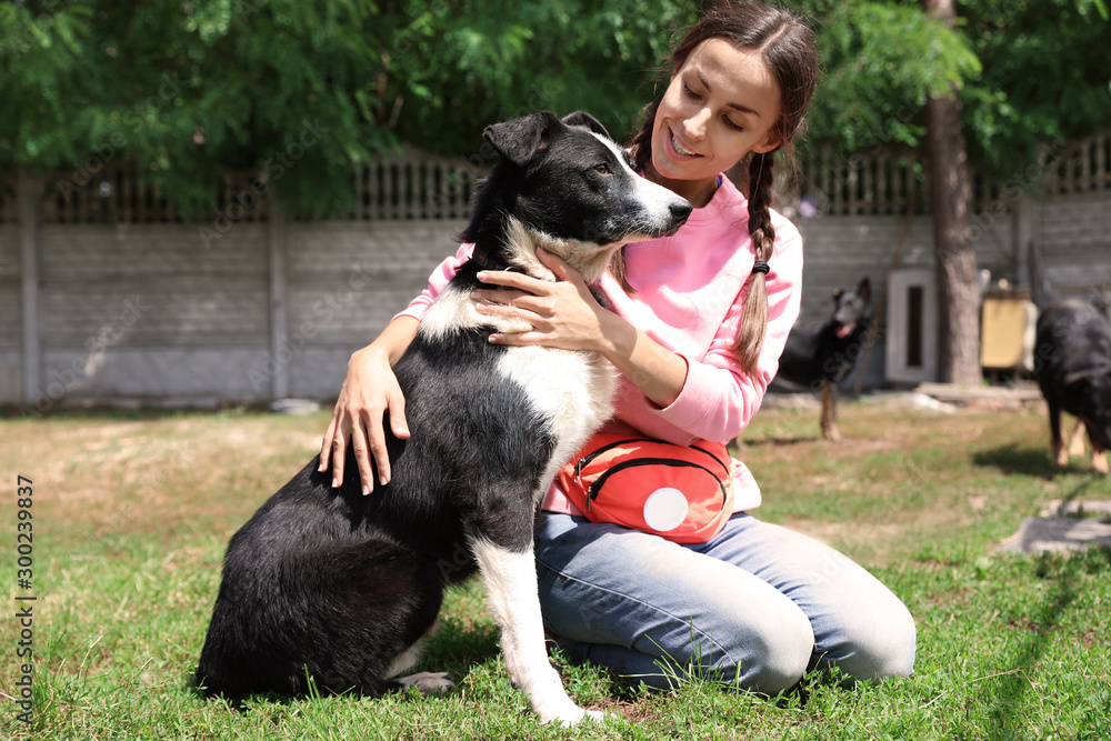 Female volunteer with homeless dog at animal shelter outdoors Female volunteer with homeless dog at animal shelter outdoors