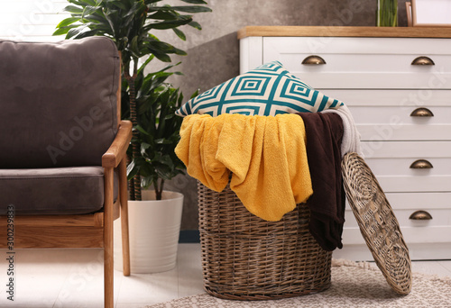 Basket with blankets and pillow near in room