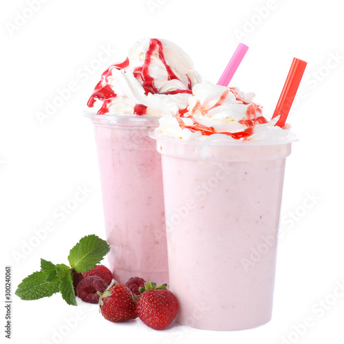 Tasty fresh milk shakes in plastic cups with ingredients on white background photo