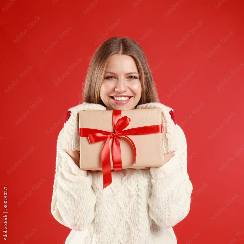 Happy young woman with Christmas gift on red background Happy young woman with Christmas gift on red background