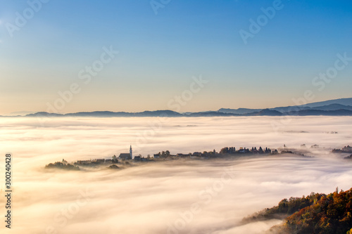Frauenberg church and other surrounding houses emerging from thick fog photo